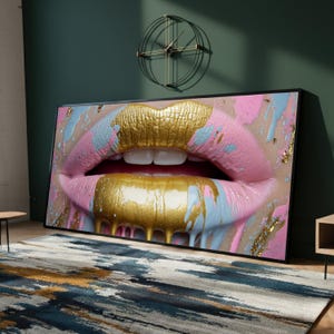 May include: A framed artwork showing a close-up of lips painted with gold lipstick and pink and blue accents. The artwork is displayed in a room with a rug and a wall clock.
