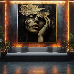 Puede incluir: Una pintura abstracta en negro y oro de la cara de una mujer. Los ojos de la mujer están cerrados y su mano descansa sobre su mejilla. La pintura está hecha en un estilo texturizado con acentos de pan de oro.