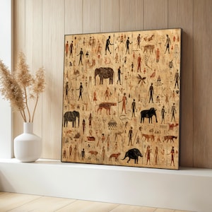 May include: Framed artwork with a tan backdrop, displaying numerous black, brown, and red figures and animal illustrations. The artwork includes elephants, people with spears, and other stylized figures, evoking a tribal or ancient theme.