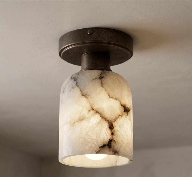 Puede incluir: Una l&aacute;mpara de techo con una pantalla con efecto m&aacute;rmol y una base de bronce oscuro. La pantalla es de color blanco crema con vetas marrones. La l&aacute;mpara tiene una sola bombilla. Dise&ntilde;ada para uso en interiores.