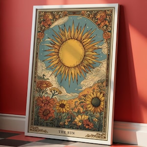 Puede incluir: Impresión artística enmarcada con una ilustración vintage del sol. La obra de arte representa un gran sol amarillo con rayos, sobre un cielo azul con nubes y un borde floral. Las palabras "THE SUN" están en la parte inferior.