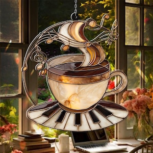 Puede incluir: Atrapasoles de taza de café de vidriera con platillo de teclas de piano y notas musicales. La taza presenta tonos marrones y crema, con un marco y cadena dorados para colgar. Un artículo decorativo único.