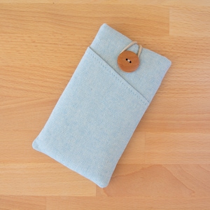 Peut inclure: Une coque de téléphone en tissu bleu clair avec une fermeture à bouton en bois.