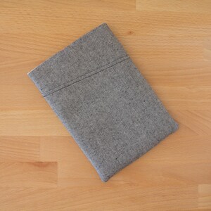 May include: A gray and black patterned fabric pouch with a stitched seam.
