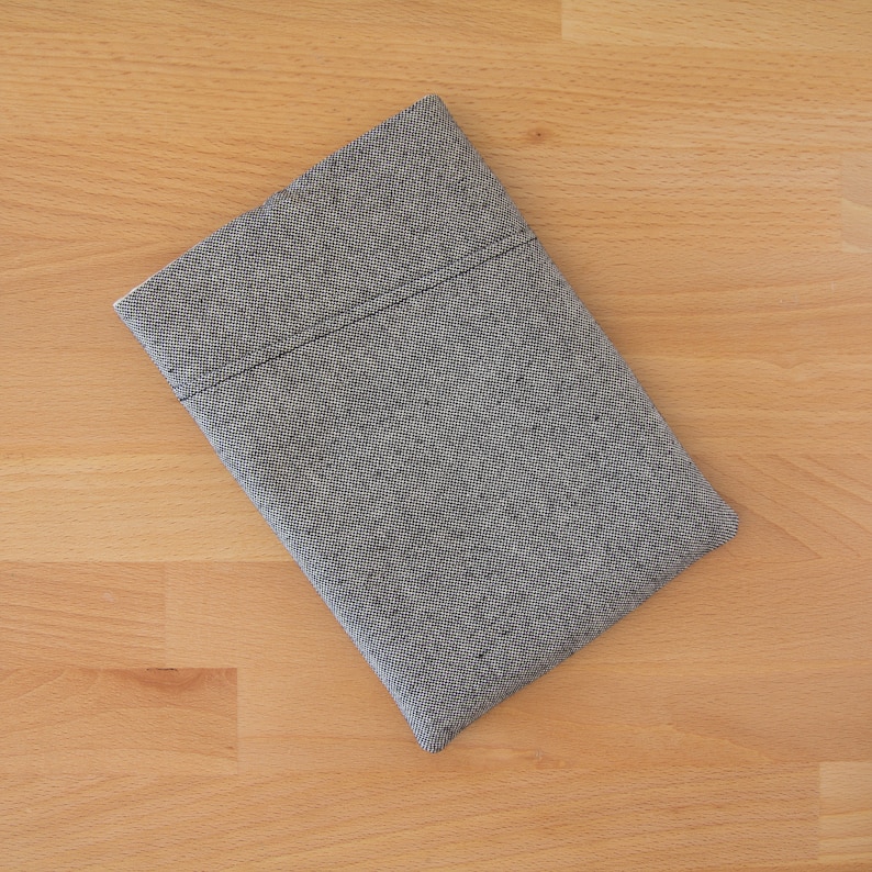 May include: A gray and black patterned fabric pouch with a stitched seam.