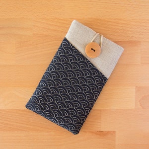 May include: A black phone case with a gold pattern of small circles and a beige linen flap with a wooden button closure.