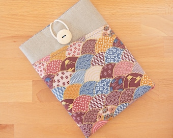 May include: A colorful fabric book cover with a geometric pattern of overlapping circles in shades of red, blue, yellow, and white. The cover has a beige fabric flap with a white button.