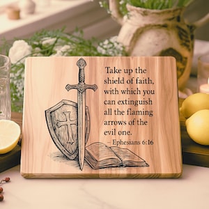 Pode incluir: Tábua de corte de madeira com um design de espada, escudo e livro aberto. O texto diz: "Tomai o escudo da fé, com o qual podereis apagar todos os dardos inflamados do Maligno. - Efésios 6:16".