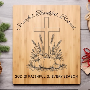 May include: A wooden cutting board with a cross, pumpkins, and wheat stalks etched into the surface. The words "Grateful. Thankful. Blessed." arc across the top, and "GOD IS FAITHFUL IN EVERY SEASON" is printed at the bottom.