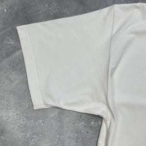 Peut inclure: Une tasse en c&eacute;ramique blanche avec une anse noire et le texte "But first, coffee" dans un style manuscrit. La tasse est pos&eacute;e sur une surface blanche. Id&eacute;ale pour les boissons chaudes.