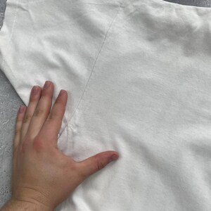 May include: A white t-shirt with a visible seam running down the shoulder. The fabric appears to be a soft cotton material. The image is taken from an overhead angle.