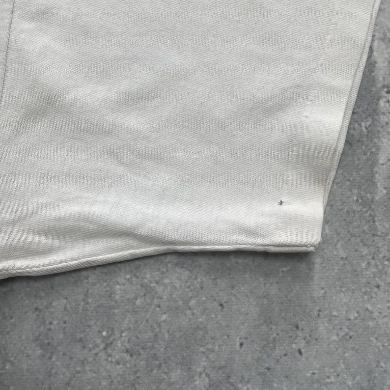 May include: A white ceramic mug with a black handle and the text "But First, Coffee" in a bold, black font. The mug is set against a neutral background, highlighting its simple design.