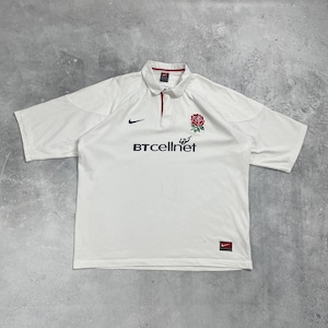 Pode incluir: Camisola de rugby branca de manga curta com gola. Apresenta um emblema de rosa vermelha e o texto "BTcellnet" em preto. Um logotipo da Nike preto &eacute; vis&iacute;vel no peito. A gola tem um detalhe vermelho.