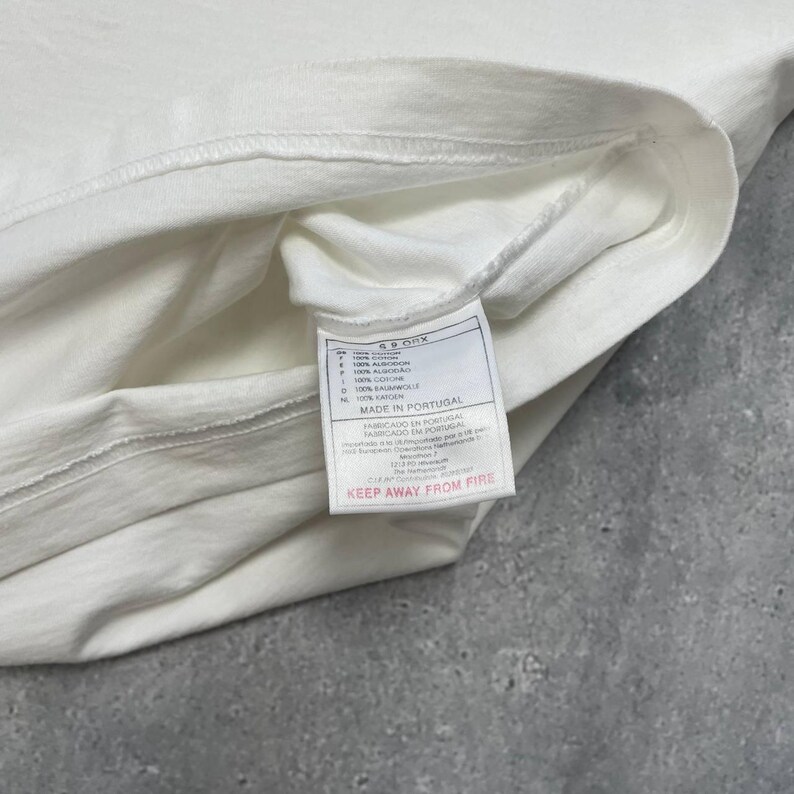 Peut inclure: Une tasse en c&eacute;ramique blanche avec une anse noire et le texte "But First, Coffee" en gras noir. La tasse est pos&eacute;e sur un fond flou, soulignant son design &eacute;pur&eacute;.