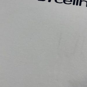 Pode incluir: Camiseta branca com a palavra "cellin" impressa em azul marinho na parte superior. O tecido parece ser um algod&atilde;o macio ou uma mistura de algod&atilde;o. A camiseta &eacute; lisa, sem outros elementos de design vis&iacute;veis.