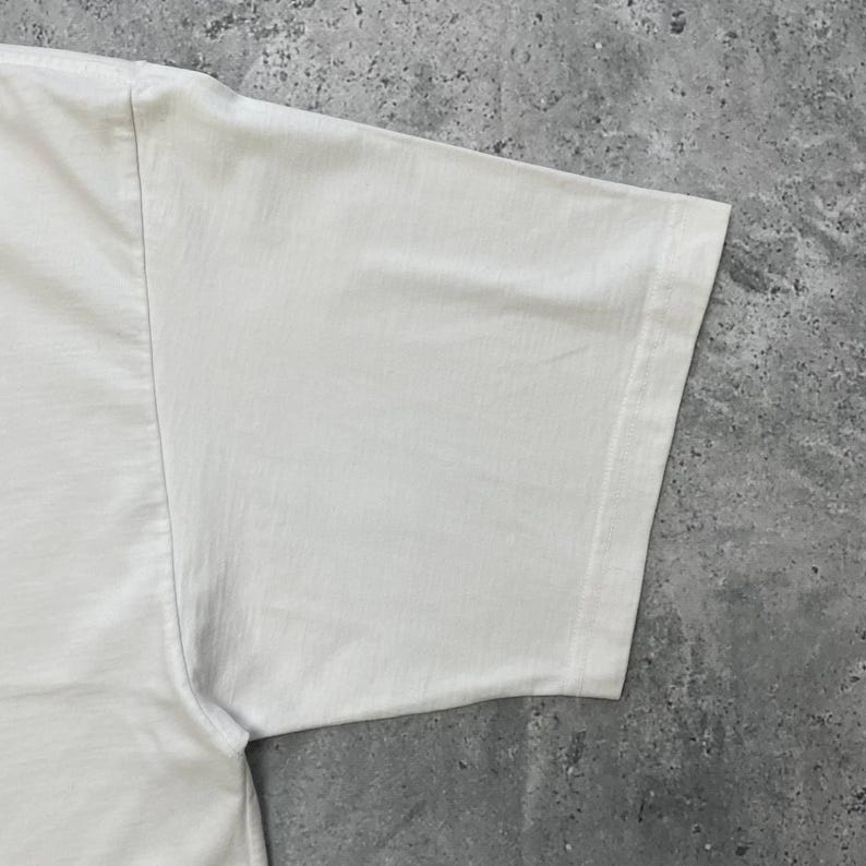 Peut inclure: Une tasse en c&eacute;ramique blanche avec une anse noire et le texte "But First, Coffee" en gras noir. La tasse est pos&eacute;e sur une surface en bois. La tasse mesure environ 10 cm de haut.