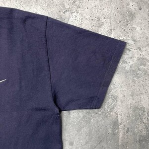 K&ouml;nnte beinhalten: Eine wei&szlig;e Keramik-Tasse mit schwarzem Henkel und dem Text "But First, Coffee" in schwarzer, handschriftlicher Schrift. Die Tasse steht auf einer wei&szlig;en Oberfl&auml;che.