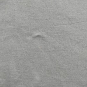 May include: A set of three ceramic mugs with a speckled, matte finish. The mugs are in shades of cream, light gray, and dark gray. Each mug has a simple, minimalist design and a rounded handle.