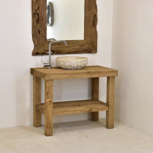 May include: A rustic wooden vanity with a natural finish, featuring a lower shelf and a stone vessel sink. A chrome faucet is installed. A large, irregularly shaped wooden mirror hangs above the vanity, creating a natural, spa-like aesthetic.