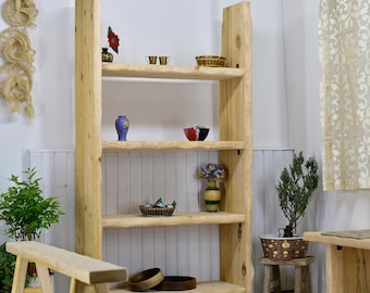 May include: A rustic wooden bookshelf with four shelves. The shelves display decorative items like vases, bowls, and small plants. The natural wood grain and live edge design give it a unique, handcrafted look. A small wooden bench and stool are in front of the bookshelf.