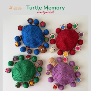 Könnte beinhalten: Vier gehäkelte Schildkröten-Memory-Spiele in Blau, Rot, Grün und Lila. Jede Schildkröte besteht aus einem großen Panzer und mehreren kleinen, passenden runden Teilen. Der Text "Turtle Memory handgehäkelt" und ein Eulen-Logo sind oben abgebildet.