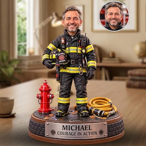 Könnte beinhalten: Eine personalisierte Feuerwehrfigur in schwarzer Schutzkleidung mit gelben Reflexstreifen, die einen Helm hält. Die Figur steht auf einem Sockel mit einem roten Hydranten, einem aufgerollten gelben Schlauch und einem Schild MICHAEL COURAGE IN ACTION.