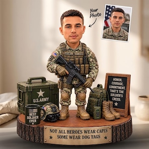 Può includere: Una statuetta bobblehead personalizzata di un soldato in uniforme mimetica con fucile, su una base in legno con la targa NOT ALL HEROES WEAR CAPES SOME WEAR DOG TAGS. Include una cassa U.S. Army, una tazza, un elmetto e un cartello.