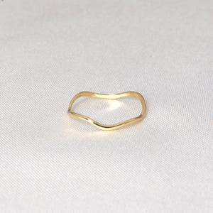 Puede incluir: Un delicado anillo de oro con un dise&ntilde;o ondulado y org&aacute;nico. La superficie lisa y pulida del anillo refleja la luz, creando un brillo sutil. El estilo minimalista lo convierte en un accesorio vers&aacute;til para el uso diario. El anillo es una joya sencilla pero elegante.