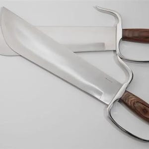 May include: Two stainless steel butterfly swords with wooden handles. The blades are wide and curved, with a polished finish. The handles have a finger loop design. The swords are displayed on a white surface.
