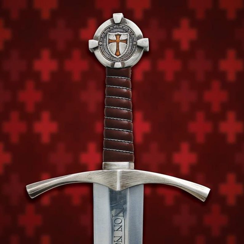 May include: A medieval sword with a silver blade and guard, featuring a brown leather-wrapped handle. The hilt has a circular emblem with a cross design. The background is a pattern of red crosses.