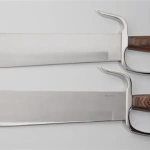 May include: Two large, polished steel blades with curved handles and wooden grips. The handles have a finger loop design. The blades are displayed on a white background.