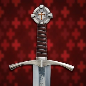 Pode incluir: Uma espada medieval com uma lâmina e guarda prateadas, e um cabo envolto em couro castanho. O pomo apresenta um design circular com um emblema de cruz. O fundo é um padrão vermelho de cruzes.
