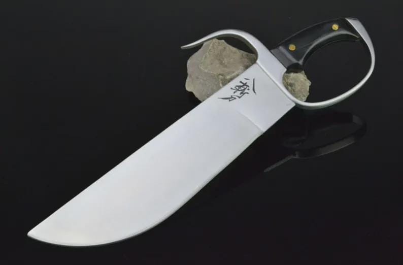 Pu&ograve; includere: Una spada a farfalla Wing Chun argento e nera con una lama curva e un design distintivo dell'impugnatura. L'impugnatura &egrave; nera con rivetti color oro. La lama ha una forma curva e un carattere cinese inciso.
