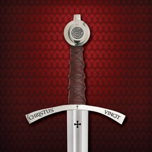 Op de afbeelding: Een middeleeuws zwaard met een zilveren pareerstang en een bruin met leer omwikkeld handvat. Het lemmet is zilverkleurig en op de pareerstang staat "CHRISTUS VINCIT". De pommel is zilverkleurig met een cirkelvormig embleem.