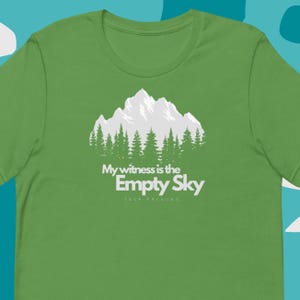 Pode incluir: Camiseta verde com um gráfico branco de uma cordilheira com árvores e o texto "My witness is the Empty Sky Jack Kerouac"