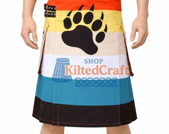 Könnte beinhalten: Ein farbenfroher Kilt mit einem braunen Ledergürtel und einer Schnalle. Der Kilt zeigt einen Bärenpfotenabdruck, den Text "SHOP KiltedCraft" und ein blaues keltisches Knotendesign. Der Kilt hat orange, gelbe, weiße, blaue und schwarze Streifen.