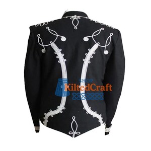 K&ouml;nnte beinhalten: Schwarze Jacke mit wei&szlig;en Stickereien. Die R&uuml;ckseite der Jacke weist aufwendige wei&szlig;e Stickereien in einem symmetrischen Design auf. Sie hat einen hohen Kragen und lange &Auml;rmel. Der Text "Shop KiltedCraft" ist sichtbar.