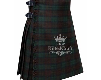 Könnte beinhalten: Ein grün-brauner Schottenrock mit zwei Lederriemen und Schnallen. Der Kilt hat einen Fransenrand und ist gefaltet. Der Text "SHOP KiltedCraft" ist auf dem Kilt aufgedruckt.