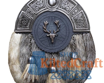 Könnte beinhalten: Ein traditioneller schottischer Kilt-Sporran. Er hat eine silberfarbene Metallkante mit keltischen Knoten und einem zentralen Oval. Die dunkelblaue Lederklappe hat ein silbernes Hirsch-Emblem. Der Sporran hat einen Pelzkörper und dekorative Quasten.