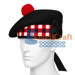 Può includere: Berretto scozzese nero Glengarry con un pompon rosso e una fascia a scacchi rossi, neri e bianchi. Il cappello ha un fiocco nero sul lato e un nastro nero. Il testo "KiltedCraft" è visibile sul cappello.