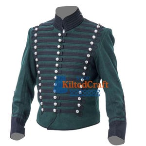 Può includere: Giacca militare verde scuro con finiture nere e bottoni argentati. La giacca ha un colletto alto e dettagli decorativi sulle maniche. Il testo "Shop KiltedCraft" è visibile in basso a destra.