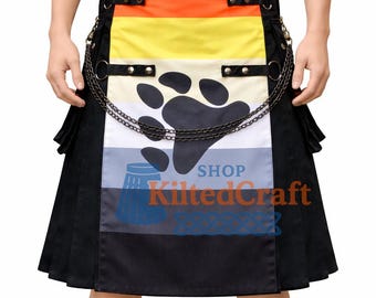 Könnte beinhalten: Ein Kilt mit einem Design der Bären-Pride-Flagge. Der Kilt hat braune, orange, gelbe, weiße, blaue und schwarze Streifen, eine Pfotenabdruck-Grafik und den Text "SHOP KiltedCraft". Er ist mit einer Kette und Metallbeschlägen versehen.