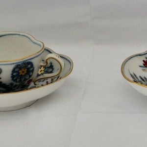 May include: Three porcelain teacups and saucers with a blue and white floral pattern. The cups have a scalloped edge and the saucers have a scalloped rim.