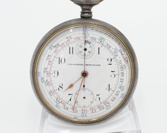 May include: A silver pocket watch with a white face and black hands. The watch has a chronograph function and a tachymeter scale. The watch is on a clear stand. The text on the watch face reads "Chronometre  Telegraphe" and "Calcule par 1000 metres de distance".