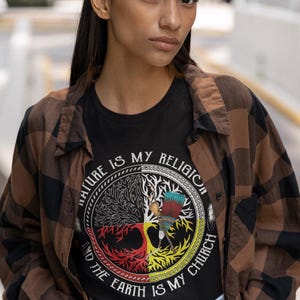 May include: A black t-shirt with a graphic of a tree with four roots, each representing a different color. The text around the tree reads "Nature is my religion and the earth is my church".
