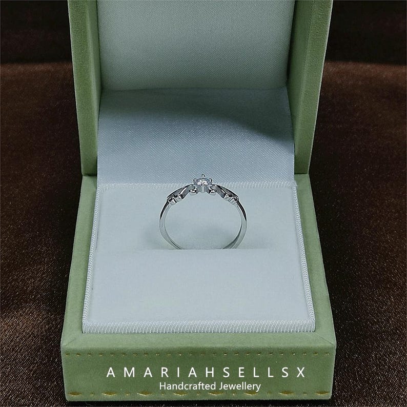 May include: A silver ring with a single diamond in a green velvet ring box. The box has the text "AMARIAHSELLS X Handcrafted Jewellery" on the bottom.