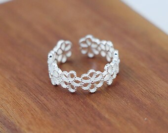 May include: A silver ring with a delicate floral design. The ring is adjustable and has a simple, elegant style.