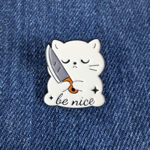 Be Nice Cartoon Cat Holding a Knife Enamel Pin – Funny Cat Lapel Brooch for Backpack, Jacket, or Gift.