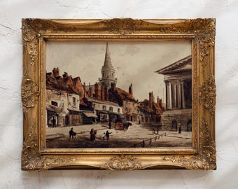 May include: An antique framed watercolor painting depicting a town square with buildings, a church steeple, and figures. The ornate gold frame enhances the artwork's vintage aesthetic. The painting's colors include browns, reds, and grays.