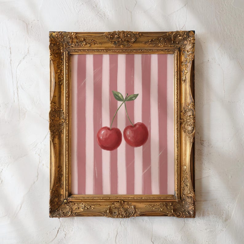 May include: A framed art print featuring two red cherries with green leaves against a pink and white striped background. The ornate gold frame adds a vintage touch to the artwork, suitable for kitchen or dining room decor.